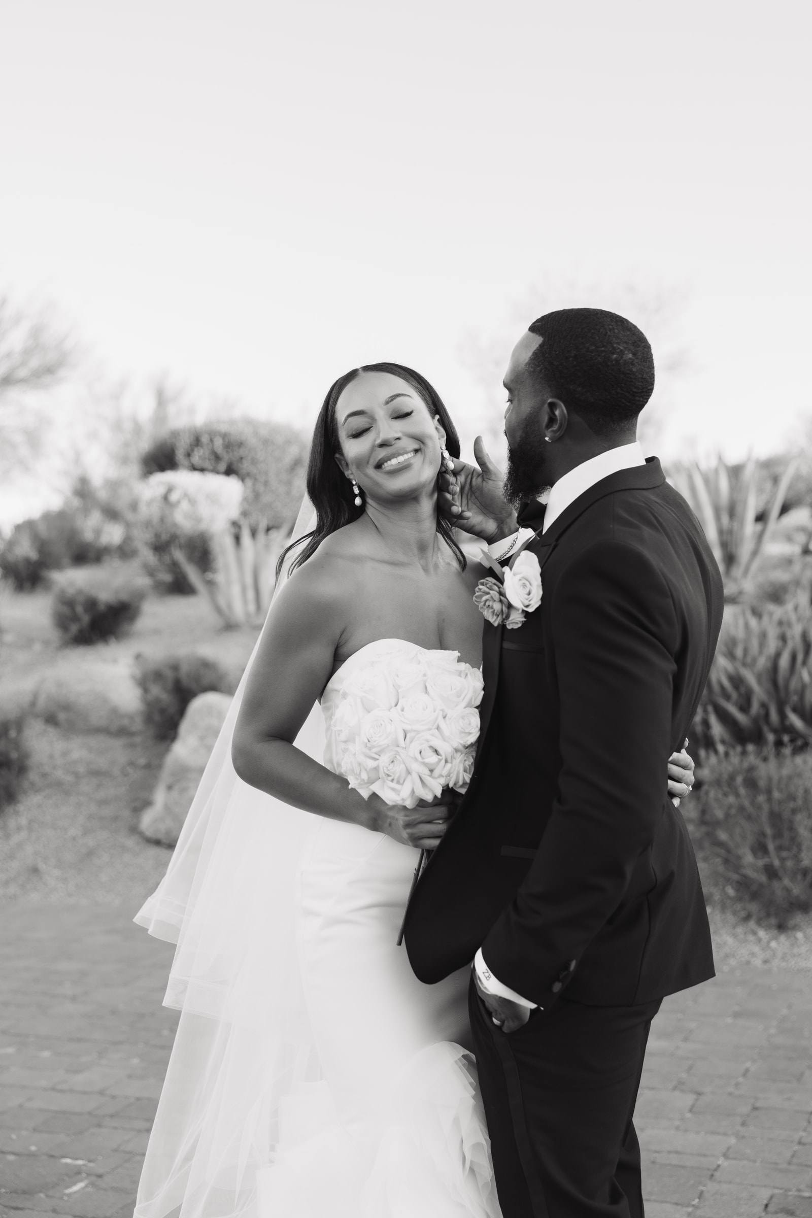A smiling bride with her groom in the Arizona desert, in black and white