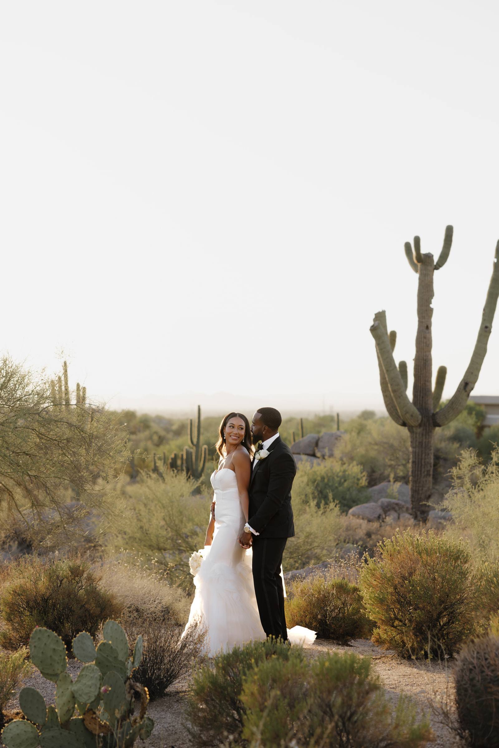 A bride and groom beside a saguaro cactus in the Arizona desert