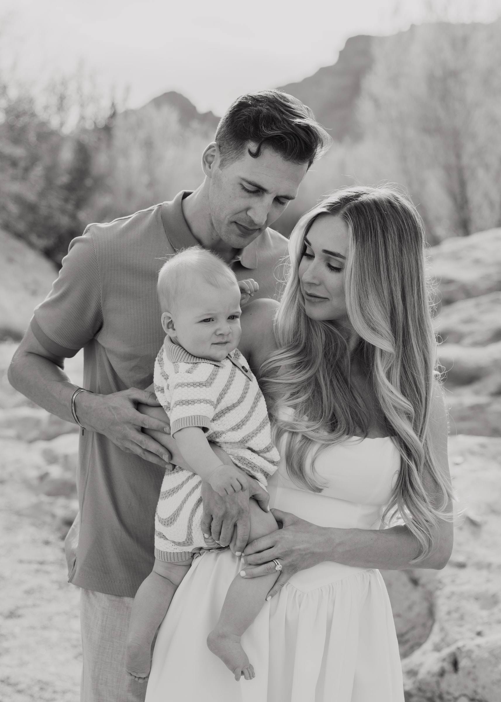 A mother and father holding their baby son, in black and white