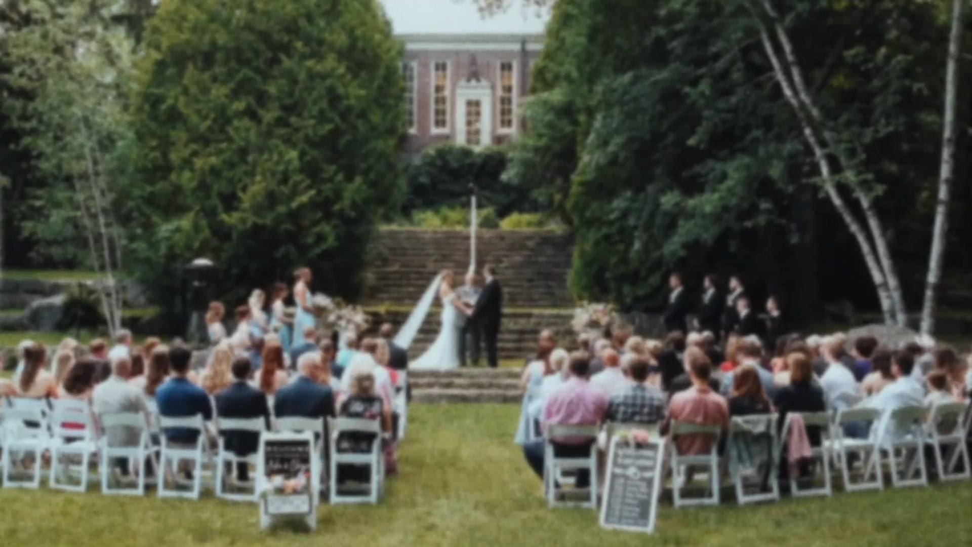 Guests seated on a lawn watching a garden ceremony in front of a brick building, from a Super8 film
