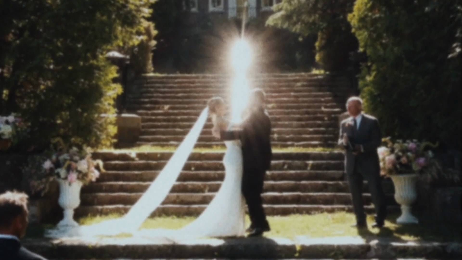 A couple at the foot of stone steps as sunlight flares behind them, from a Super8 film