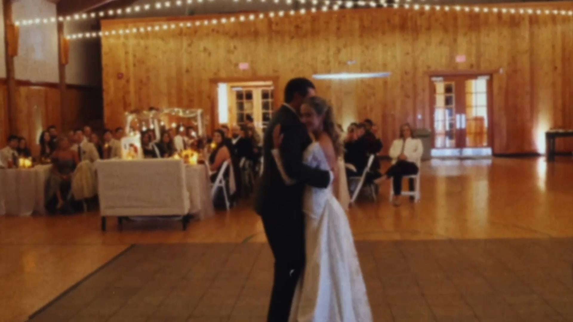 A couple sharing their first dance in a wood-panelled hall, from a Super8 film