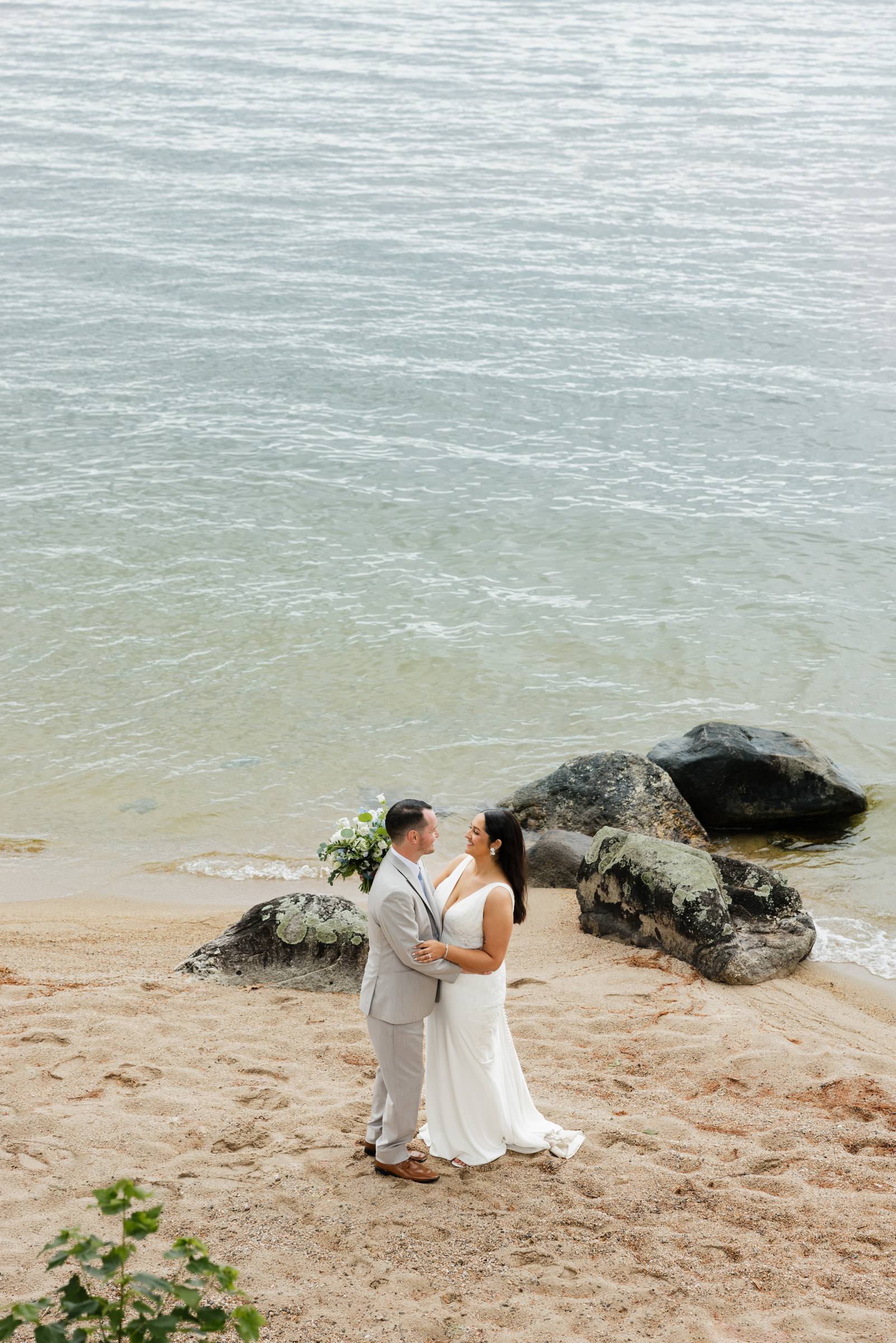 A bride and groom on a rocky Maine beach beside the sea