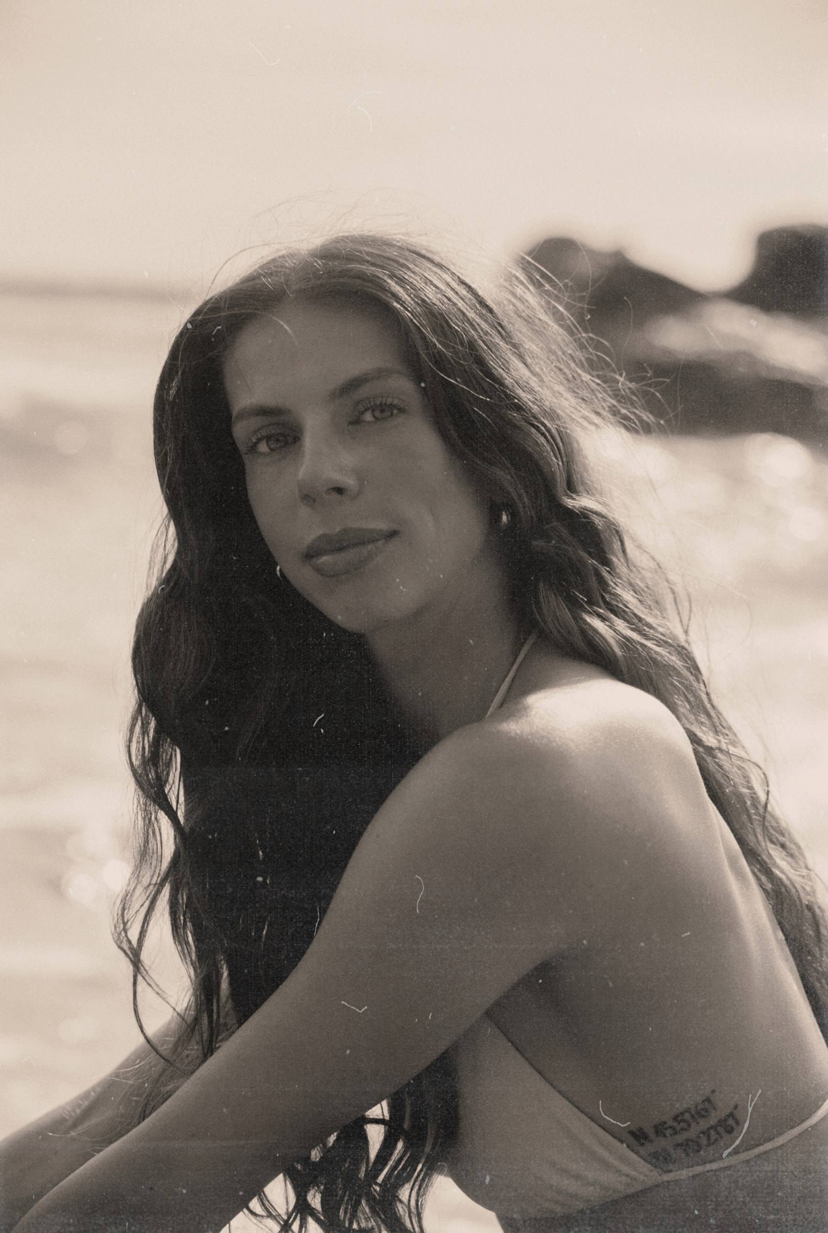 Victoria sitting by the sea, looking into the camera